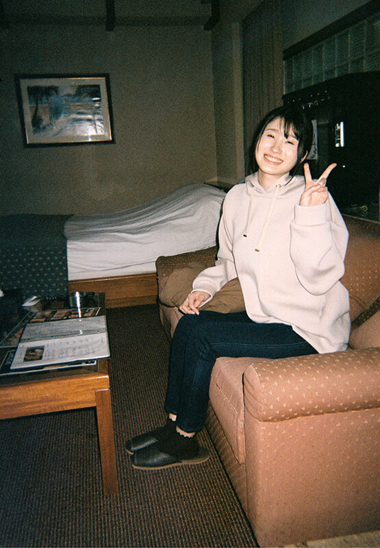 沙月ふみの 部屋のソファでパーカーとデニムの私服姿、ピースサインのカット